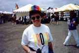 Person smiling, standing in front of booths at Pride festival, 1992